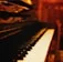A close-up photo of a vintage Blüthner grand piano keyboard with warm lighting.